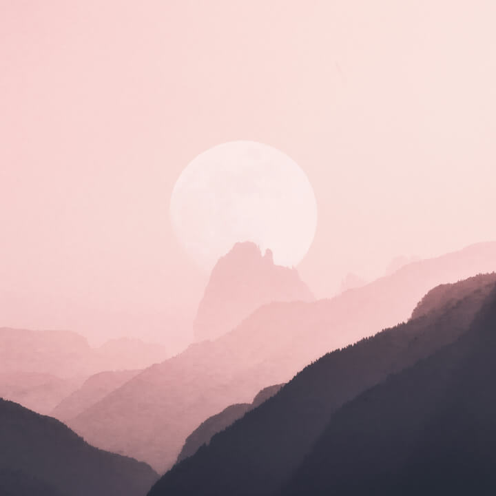 A large sun sets behind rolling hills in a hazy, pink landscape, creating a serene silhouette effect.